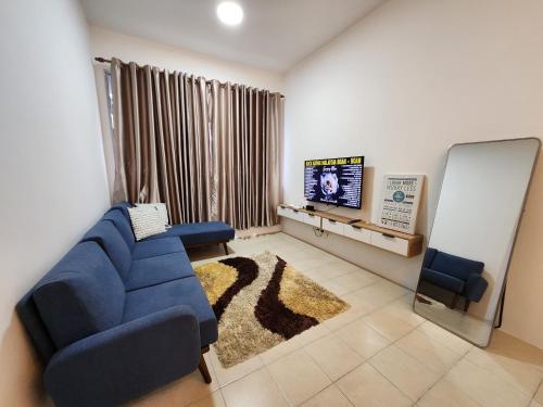 ein Wohnzimmer mit einem blauen Sofa und einem TV in der Unterkunft Homestay D'Rumahku in Kampong Parit