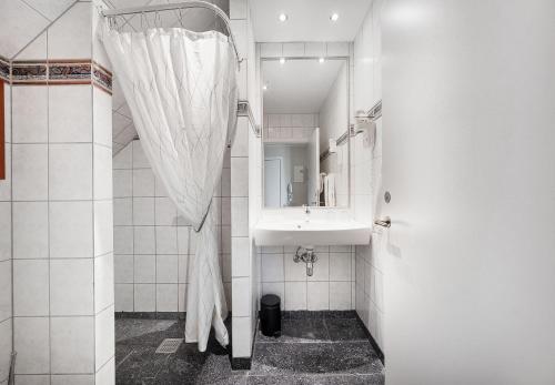 Baño blanco con lavabo y espejo en Hotel Ringkøbing, en Ringkøbing