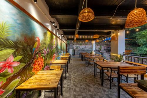 a row of tables and chairs in a restaurant with a mural at Cat Ba Xanh Spring Garden Hotel in Cat Ba