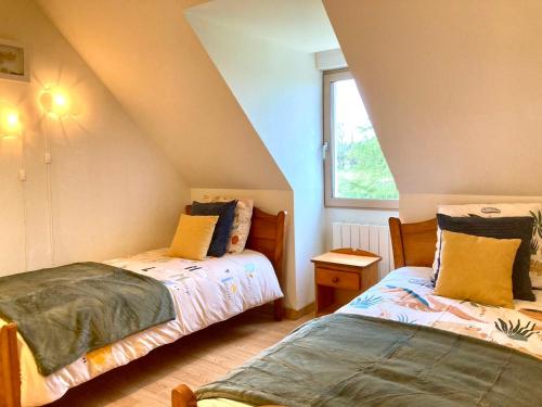 a attic room with two beds and a window at Double J in Formigny