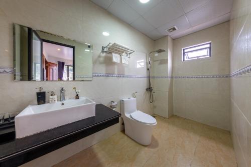 a bathroom with a sink and a toilet and a mirror at Cat Ba Xanh Spring Garden Hotel in Cat Ba