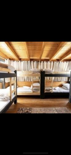 a bedroom with three bunk beds with wooden ceilings at הוילה הסודית שלי in Kefar H̱ananya