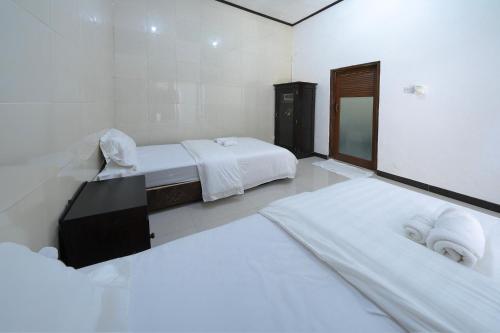 a white room with two beds and a mirror at Dive & Dwell Tulamben in Tulamben