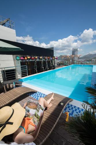 two women laying on lounge chairs next to a swimming pool at TND Hotel in Nha Trang