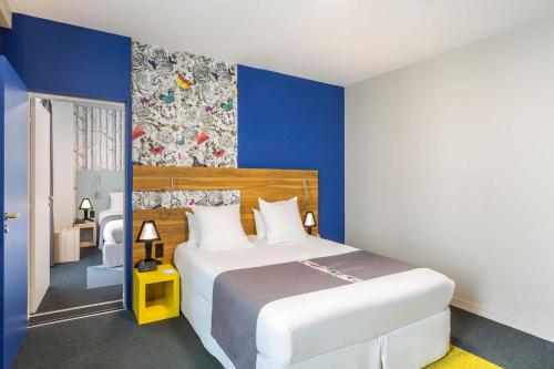 a bedroom with a large bed with blue walls at Best Western Hotel De Paris in Laval