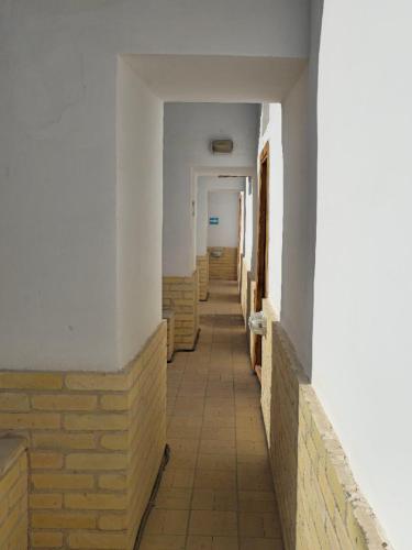 an empty hallway of a building with a brick wall at Orient Star Khiva Hotel- Madrasah Muhammad Aminkhan 1855 in Khiva