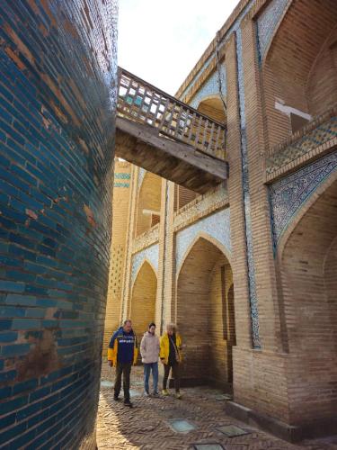a group of people standing next to a brick building at Orient Star Khiva Hotel- Madrasah Muhammad Aminkhan 1855 in Khiva