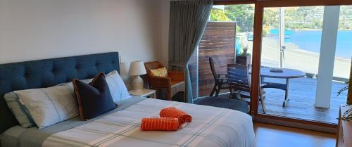 a bedroom with a bed with an orange pillow on it at New luxury waterfront accommodation in Dunedin