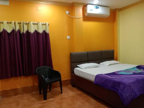 a bedroom with a bed and a chair and a window at Hotel Sahoo Palace Near Sea Beach in Puri