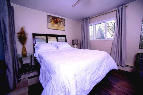 a bedroom with a large bed with white sheets and a window at KING SUITE ON 16TH AVE in Anchorage
