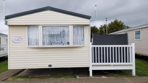 a mobile home with a window and a porch at SKYLA VISTA Clacton-on-Sea in Clacton-on-Sea
