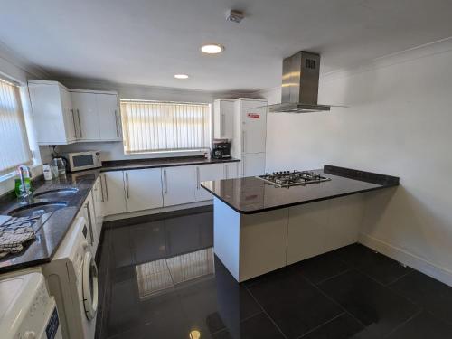 a kitchen with white cabinets and a black counter top at OYO Ormsby Townhouse in Middlesbrough