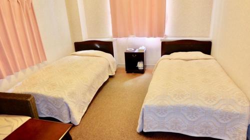 a room with two beds and a table at パームビーチリゾートホテル in Oshima