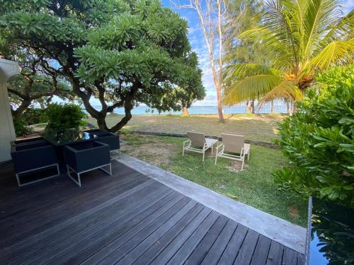 a wooden deck with chairs and a table on the beach at Villa No2 - Sun Tan Palmar in Belle Mare