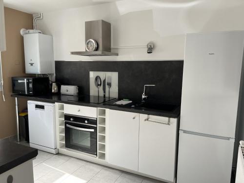 une cuisine avec des armoires blanches et un comptoir noir dans l'établissement La Tannerie des Bourgeois, à Calais