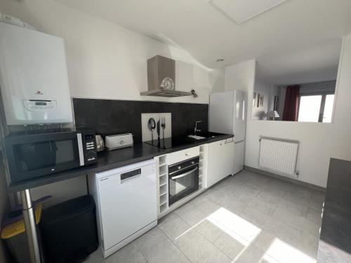 une cuisine avec des appareils blancs et un comptoir noir dans l'établissement La Tannerie des Bourgeois, à Calais