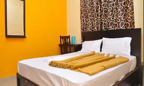 a bed with white sheets and a yellow wall at FabExpress Century Gardens in Bangalore