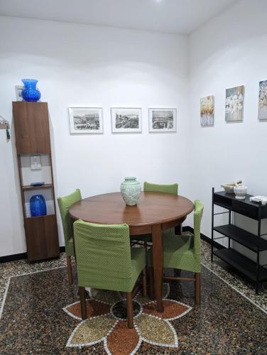 uma sala de jantar com uma mesa de madeira e cadeiras verdes em CasaLeonardo em Gênova