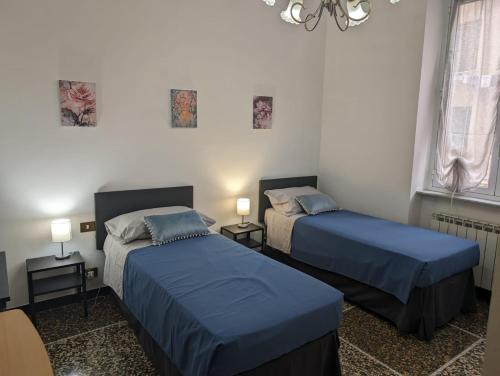um quarto com 2 camas, 2 candeeiros e um lustre em CasaLeonardo em Gênova