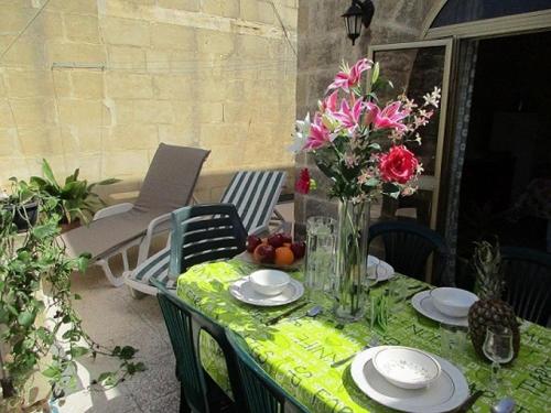 a table with a vase of flowers on a patio at Serenity - Bellevue Gozo in Xlendi