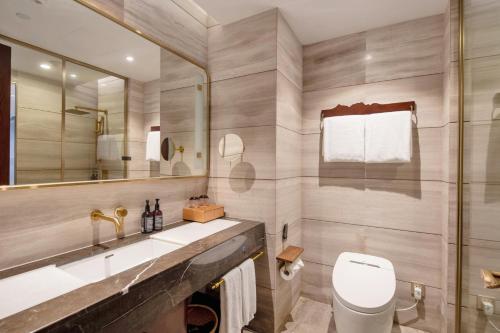 a bathroom with a toilet and a sink and a mirror at New Century Hotel Qianchao Hangzhou in Hangzhou