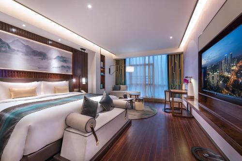um quarto de hotel com uma cama grande e uma televisão grande em New Century Hotel Qianchao Hangzhou em Hangzhou