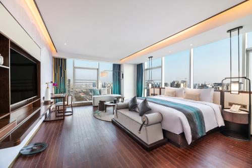 um quarto grande com uma cama grande e um sofá em New Century Hotel Qianchao Hangzhou em Hangzhou
