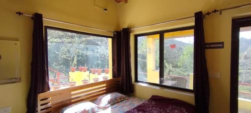 a bedroom with two windows and a bed in a room at Ababeel Homestay, Hartola in Rāmgarh