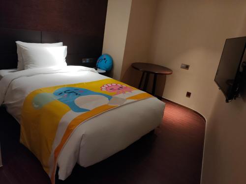 a hotel room with a bed with a colorful blanket at New Century Hotel Qianchao Hangzhou in Hangzhou