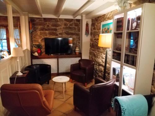 a living room with leather chairs and a television at Hotel Puerto Arnela in Camariñas