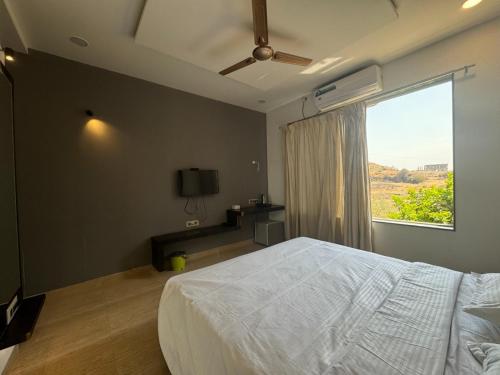 Zestin Hill Resort Lonavala في لونافالا: غرفة نوم بسرير كبير ونافذة