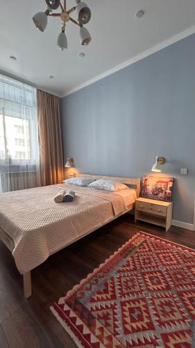 1 dormitorio con cama y alfombra en el suelo en Sunrise, en Almaty