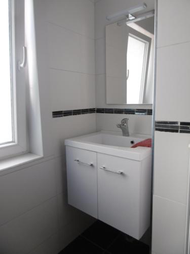 La salle de bains blanche est pourvue d'un lavabo et d'un miroir. dans l'établissement Buisseret, à Seneffe