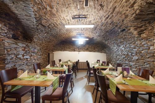 a restaurant with wooden tables and chairs and a brick wall at Hotel Mosella in Bullay