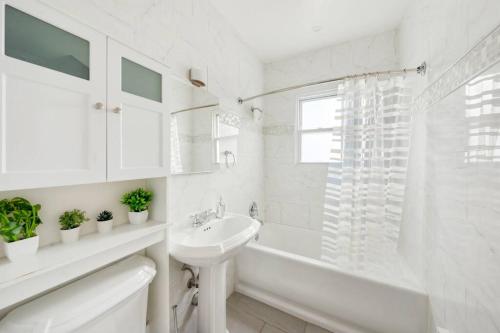a white bathroom with a sink and a bath tub at 3BD Luxury Retreat in NY with Free Parking in Yonkers