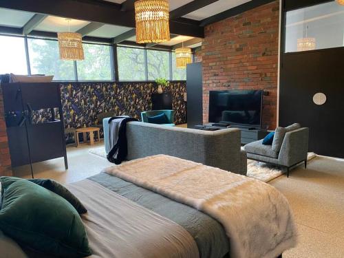 a bedroom with a bed and a couch and a television at Sibbel House- Luxurious Mid-Century Modern Home, Yarra Valley in Healesville