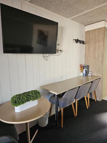 a room with two tables and a tv on a wall at Cameo Inn Motel in West Wyalong