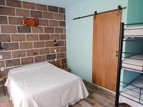 Cette chambre dispose d'un lit et d'un mur en briques. dans l'établissement Casa orquídea, à Oacalco