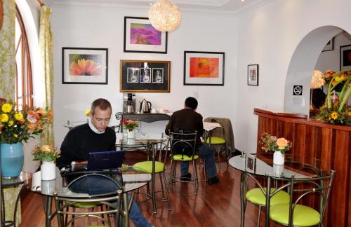 two men sitting at tables in a restaurant with a laptop at Boutique Hotel Casa Foch in Quito