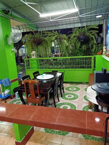a restaurant with tables and chairs and a green wall at Greenhouse homestay betong in Betong