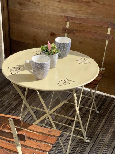 a table with two cups and a plant on it at Le Caux ´Sy in Senneville-sur-Fécamp