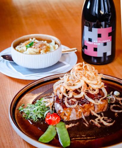a table with a plate of food and a bottle of wine at Hotel-Restaurant Kreuzberghof Tagungs- und Veranstaltungshotel in Tiefenbach