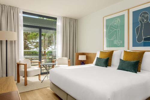 a bedroom with a large white bed and a table and chairs at AC Hotel Gava Mar in Gavà