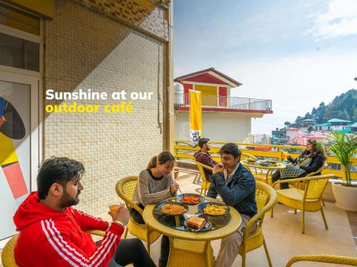 un grupo de personas sentadas en una mesa comiendo comida en The Hosteller Mcleodganj, Bhagsu en McLeod Ganj