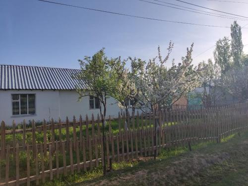une clôture en bois devant une maison blanche dans l'établissement Нуска конок уйу, à Kasymbek