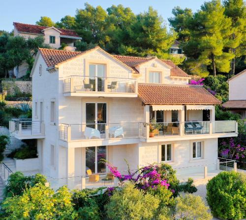 a large white house with balconies and trees at VILLA PHILIPPA - luxurious five-room villa on the island of BRAČ - idyllic location right by the sea - incredible view of the sea bay - VIP services - BURALUX properties in Sutivan