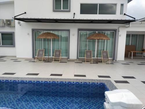 a pool with chairs and umbrellas next to a house at Evening/Night de Ville-50pax Private Pool BBQ in Ipoh