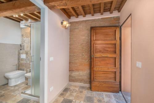 bagno con porta in legno e servizi igienici. di Casa Serena a Vicopisano