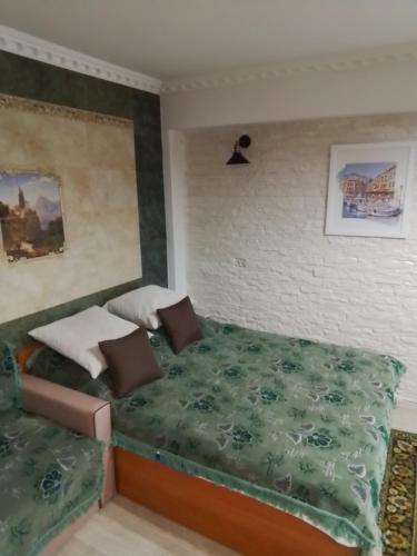 een slaapkamer met een bed met een groen dekbed bij Лофт в морском стиле in Öskemen