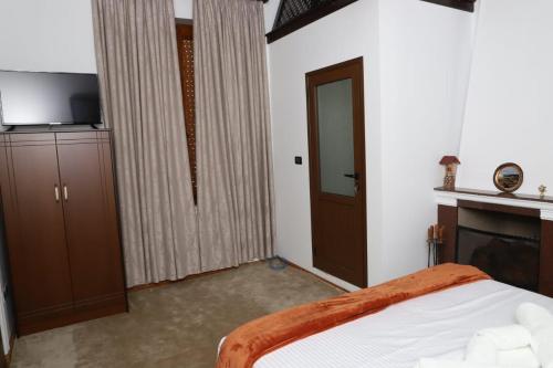 Schlafzimmer mit einem Bett, einem TV und einem Kamin in der Unterkunft Villa Palma Center in Berat